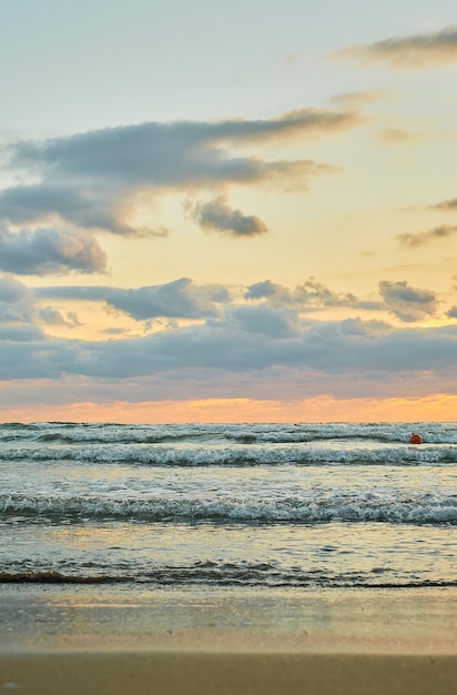 Playa de arena puesta de sol sobre el mar con nubes coloridas luz solar naranja Marco vertical puestas de sol de otoño temporada de terciopelo de otoño temprano La idea de un fondo o pantalla de bienvenida