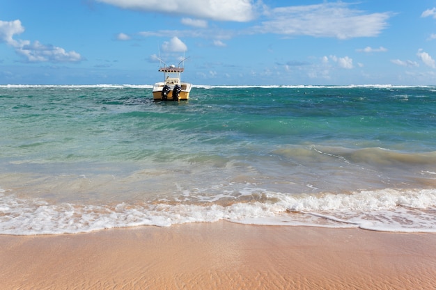 Playa con barco en el mar y cielo azul.