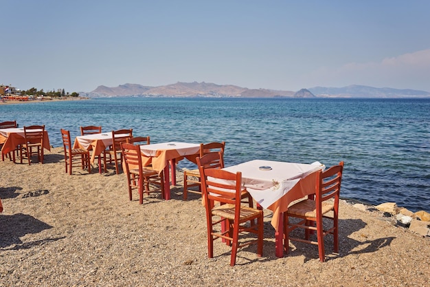 Playa griega con mesas y sillas azules tradicionales