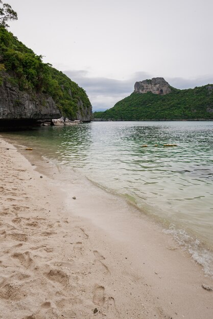 Playa en isla tropical. Agua azul clara, arena, nubes.