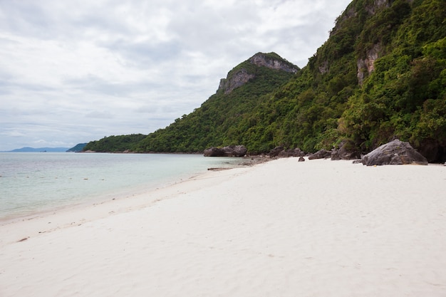 Playa en isla tropical. Claras aguas azules, arena, nubes.