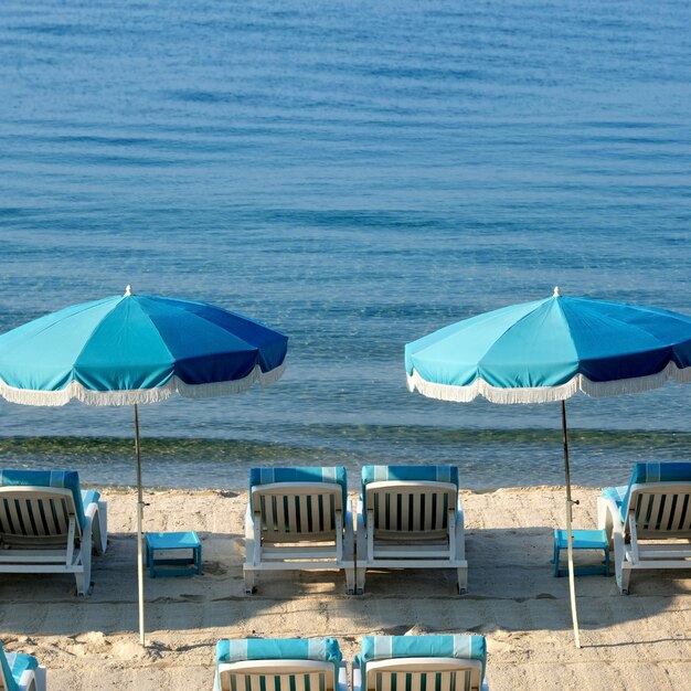 Playa mediterránea con sombrillas y sillas.