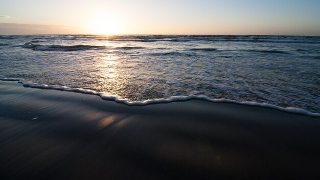 Playa del océano con olas de luz sobre la arena