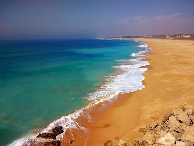 Foto gratuita playa rodeada por el mar bajo la luz del sol en cádiz, españa.