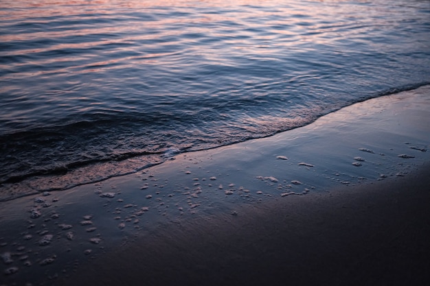 Playa rodeada por el mar bajo la luz del sol durante la puesta de sol