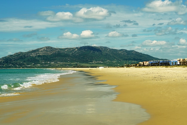 Foto gratuita playa rodeada por el mar y moutnains bajo la luz del sol en tarifa, españa