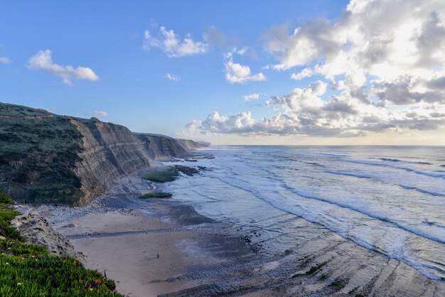 Playa rodeada de rocas y el mar bajo un cielo nublado durante el amanecer