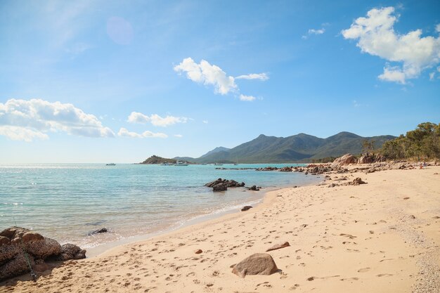 Playa rodeada de rocas y el mar con colinas cubiertas de vegetación