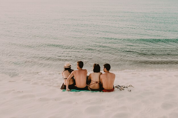 Playa tranquila con dos mujeres y dos hombres sentados cerca del agua