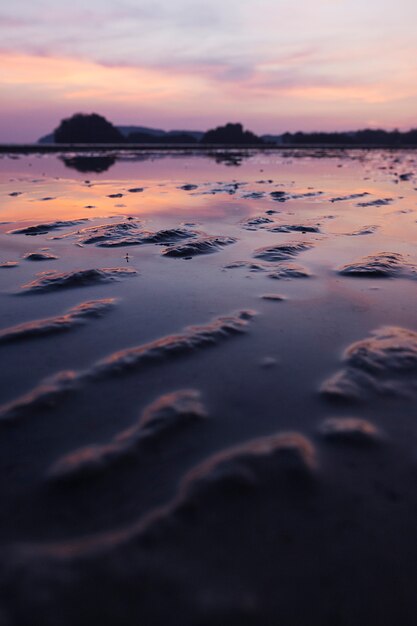 Playa tropical de arena con cielo dramático durante la marea baja.