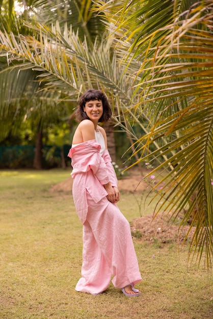 Foto gratuita en pleno crecimiento, joven y delgada mujer morena caucásica sonríe modestamente con los ojos abatidos al aire libre concepto de tiempo de descanso