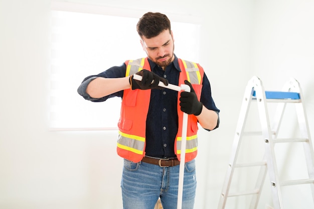 Plomero enfocado que trabaja en el montaje de tuberías para instalar el sistema de plomería mientras construye una nueva casa