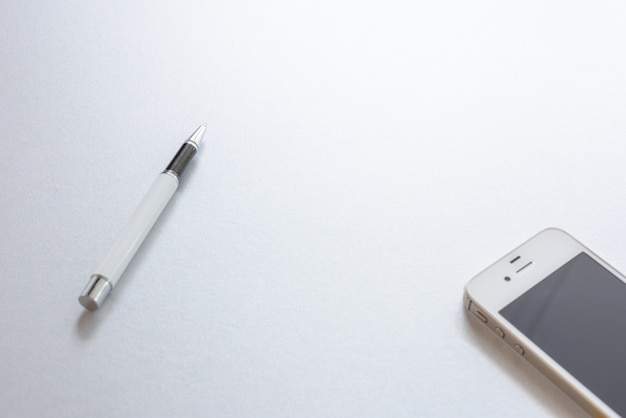 Una pluma blanca y un teléfono blanco sobre fondo blanco.