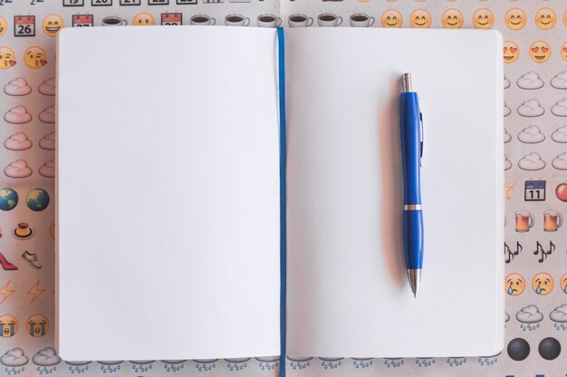 Pluma y cuaderno sobre fondo emoji