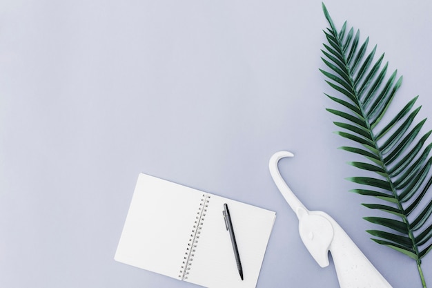 Pluma sobre el cuaderno, unicornio blanco y hoja sobre fondo blanco