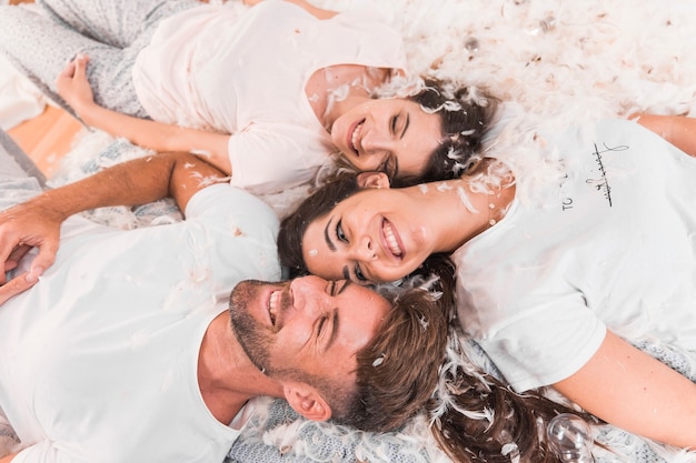 Foto gratuita pluma suave blanca sobre los amigos acostados en la cama