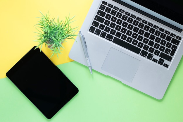 Pluma en el teclado cerca de la tableta y la planta