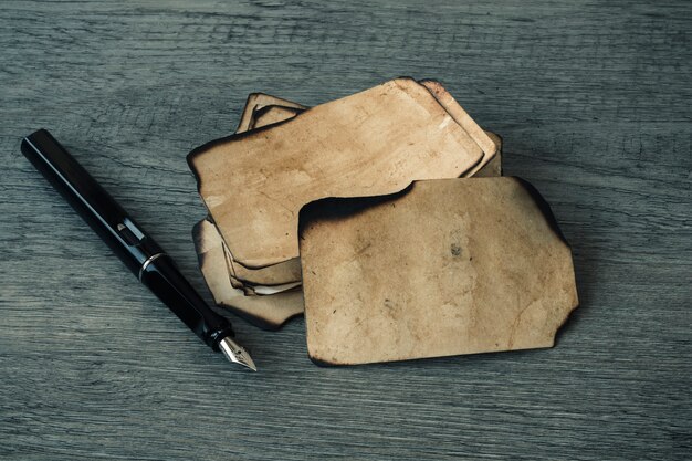 Pluma de tinta cerca de hojas pequeñas de papel viejo