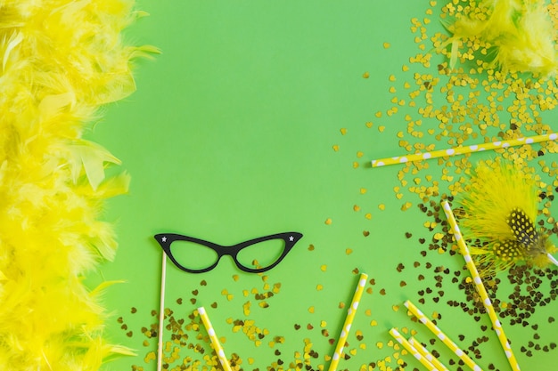 Foto gratuita plumas de color amarillo con confeti y gafas negras