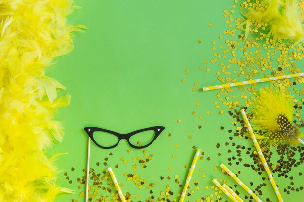 Plumas de color amarillo con confeti y gafas negras