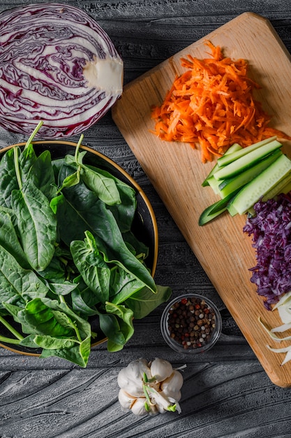 Un poco de ensalada de verduras con verduras en rodajas, verdes sobre fondo de madera oscura, vista superior.