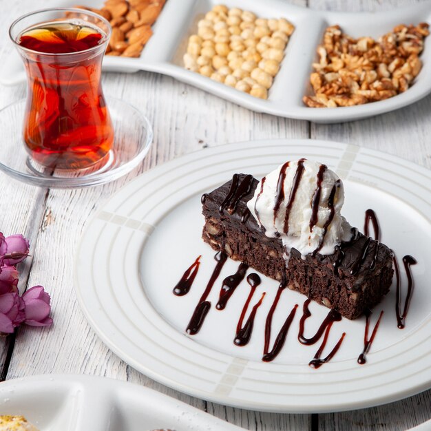 Un poco de postre con té, nueces en una placa en el fondo de madera blanco, opinión de alto ángulo.