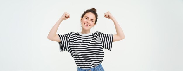 Foto gratuita poder femenino y feminismo joven que se siente empoderada y fuerte flexionando sus bíceps mostrando músculos