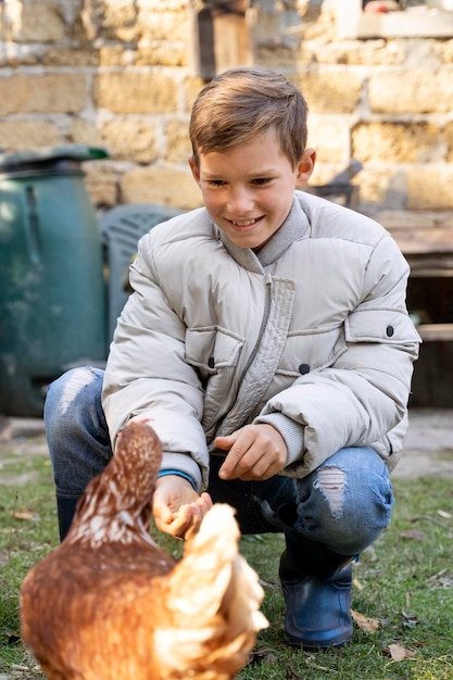 Foto gratuita pollito de alimentación de niño de tiro completo