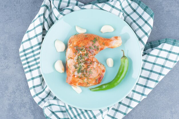 Pollo adobado con ajo y pimienta en placa azul.