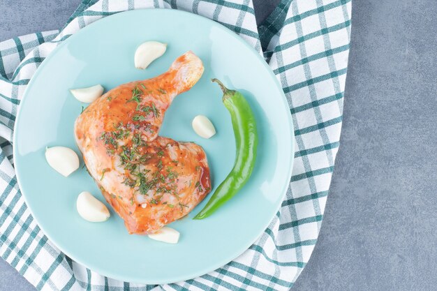 Pollo adobado con ajo y pimienta en placa azul.