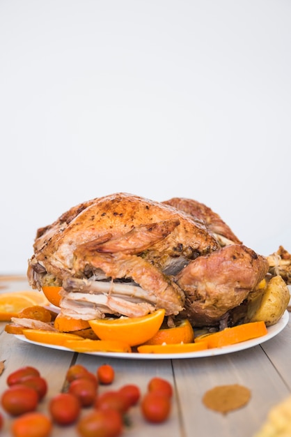 Pollo al horno con naranjas en el fondo de la pared blanca