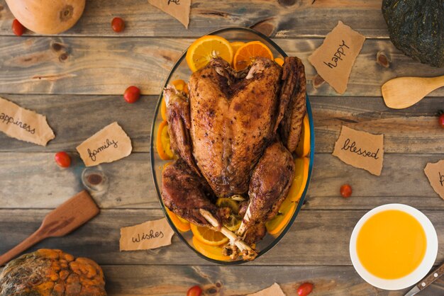 Pollo al horno con naranjas en mesa de madera