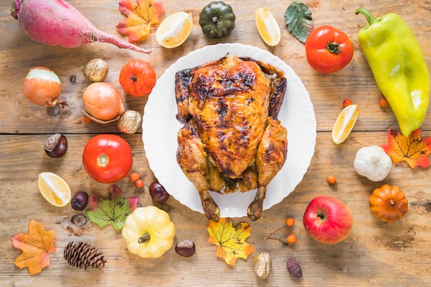 Pollo al horno entre verduras y frutas.