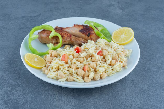 Pollo asado y arroz con garbanzos en un plato blanco.