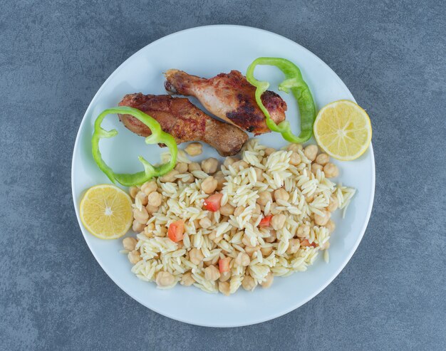 Pollo asado y arroz con garbanzos en un plato blanco.