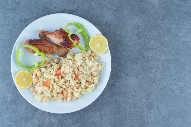 Pollo asado y arroz con garbanzos en un plato blanco.