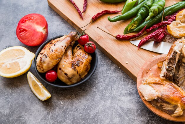 Pollo asado con chiles y tomate sobre fondo de concreto