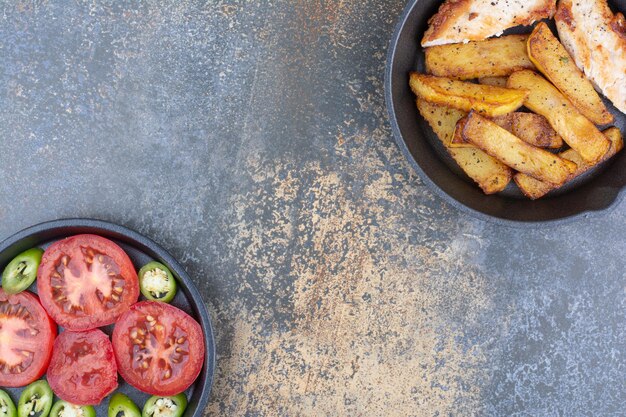 Pollo asado y patatas en sartén con plato de verduras. Foto de alta calidad