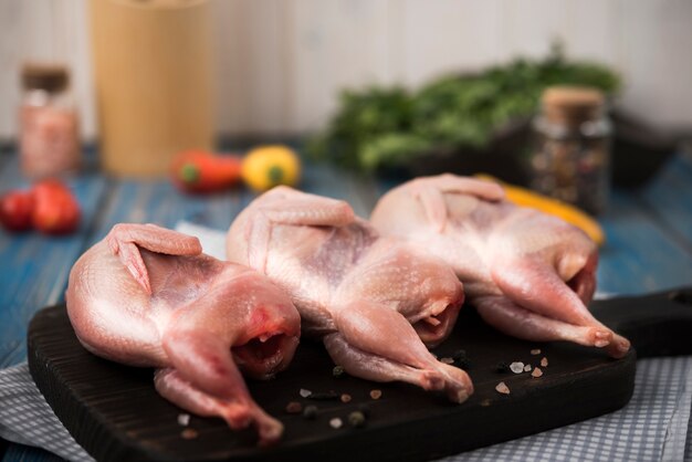 Pollo crudo sobre tabla de madera con ingredientes