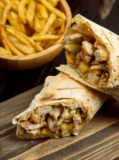 Pollo duro, shaurma dentro de un lavash con papas fritas sobre tabla de madera