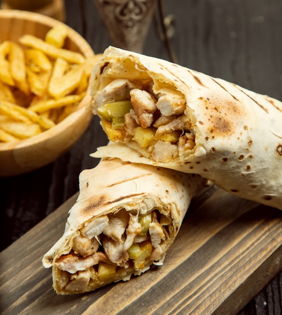 Pollo duro, shaurma con lavas y papas fritas sobre tabla de madera