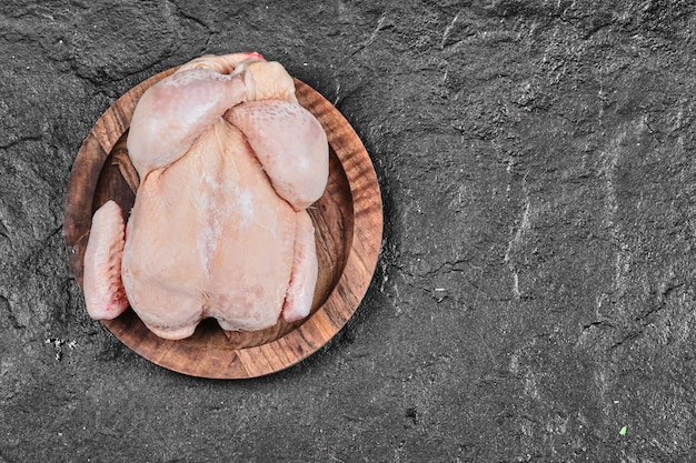 Pollo entero crudo en placa de cerámica aislada sobre superficie blanca