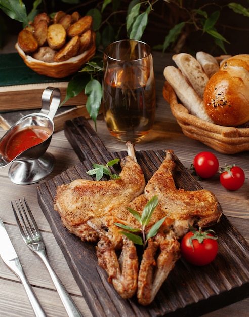 Pollo entero a la parrilla con salsa de tomate y hierbas sobre tabla de madera