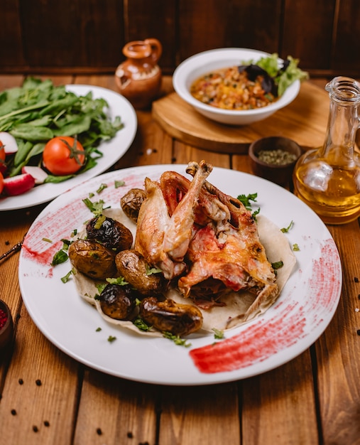 Pollo entero a la parrilla servido con papas a la parrilla