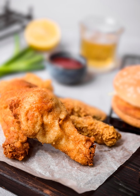 Pollo frito de alto ángulo en la tabla de cortar con hamburguesa