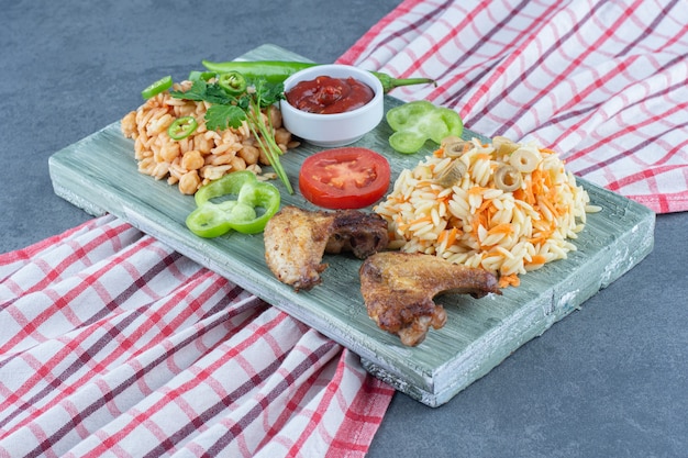 Pollo frito con arroz y pasta sobre tabla de madera.