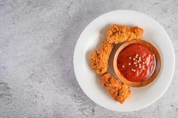 Pollo frito crujiente en un plato blanco con salsa de tomate