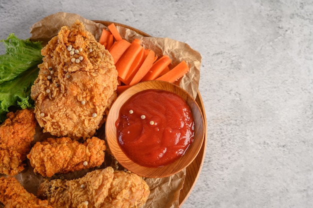 Pollo frito crujiente en un plato de madera con salsa de tomate y zanahoria