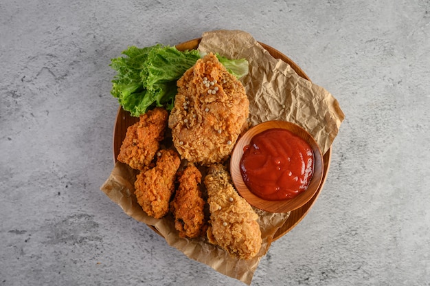 Pollo frito crujiente en un plato de madera con salsa de tomate