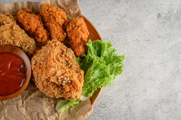 Pollo frito crujiente en un plato de madera con salsa de tomate